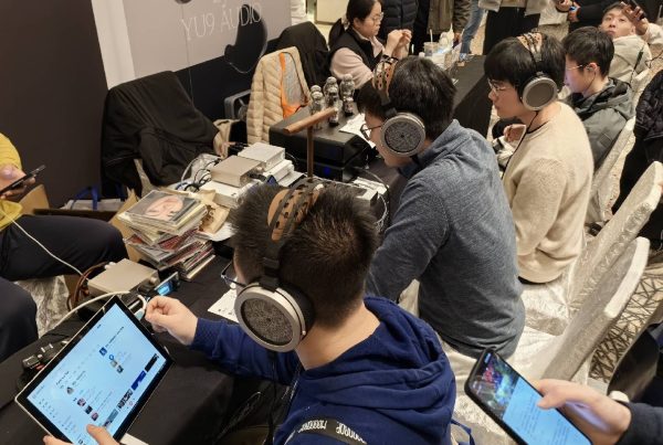 Listeners evaluating Hongshu Audio equipment at an audio show table / 展会桌面上的虹曙试听设备